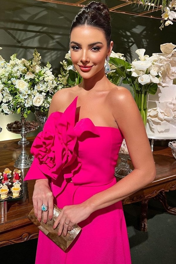 Madrinha de casamento usando vestido longo pink com flor 3D modelada com o mesmo tecido do vestido
