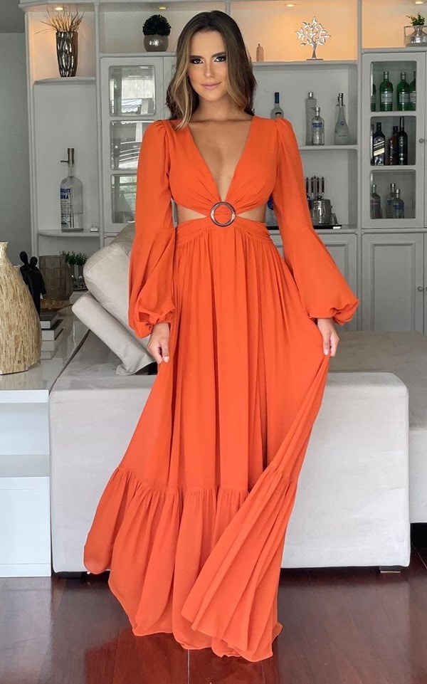 Vestido longo laranja com mangas longas e recorte na cintura.