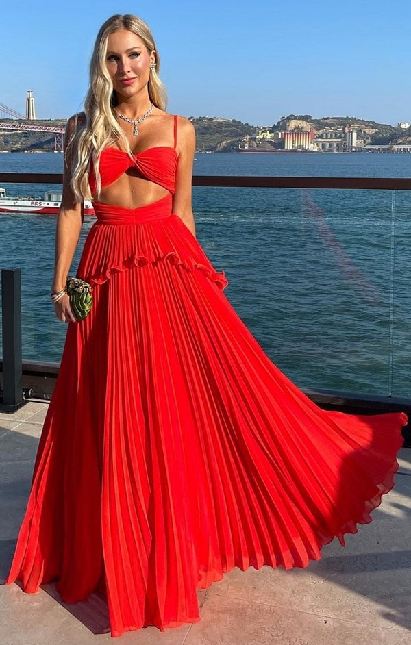 convidada de casamento usando vestido longo vermelho plissado com alças finas e recorte frontal 