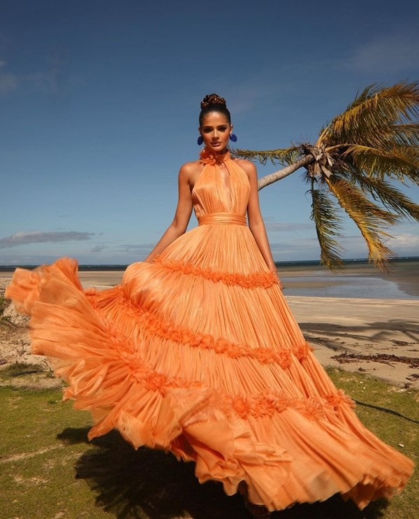 Thassia Naves no casamento de Marcela Tranchesi usando vestido de festa terracota claro modelo frente única com saia ampla. O casamento é na praia e o penteado é oreso com brincos azul royal