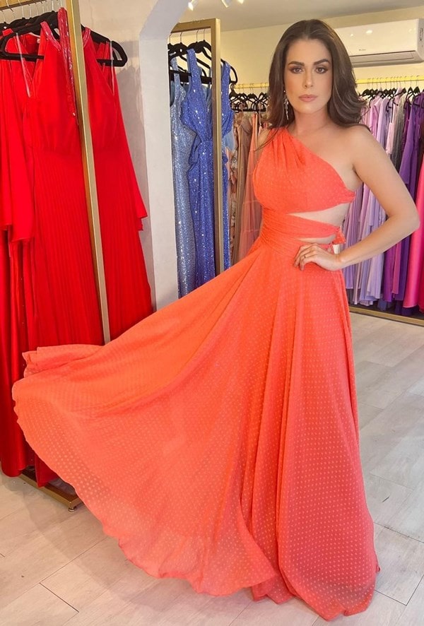 modelo usando vestido laranja modelo um ombro só   com recortes  em uma lateral do vestido.