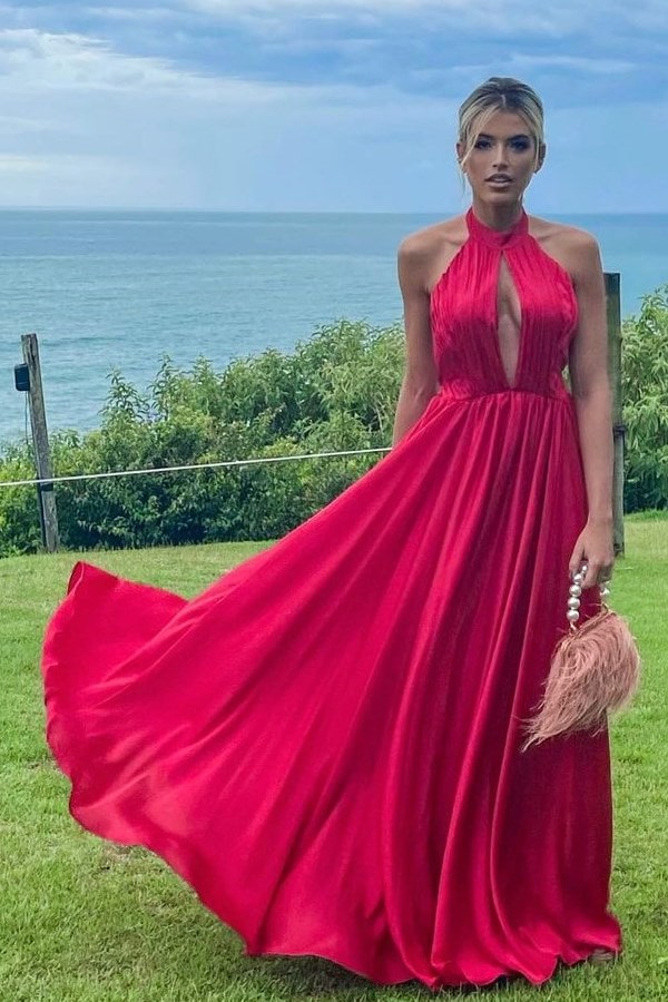 Convidada de casamento na praia usando vestido longo vermelho frente única com decote e saia fluida