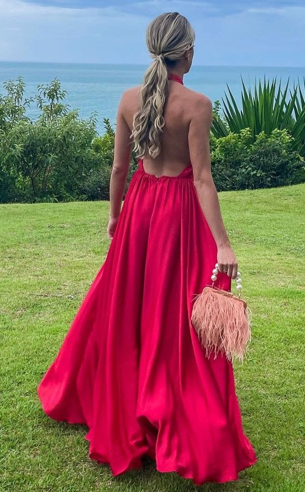 Convidada de casamento na praia usando vestido longo vermelho fluido com decote nas costas