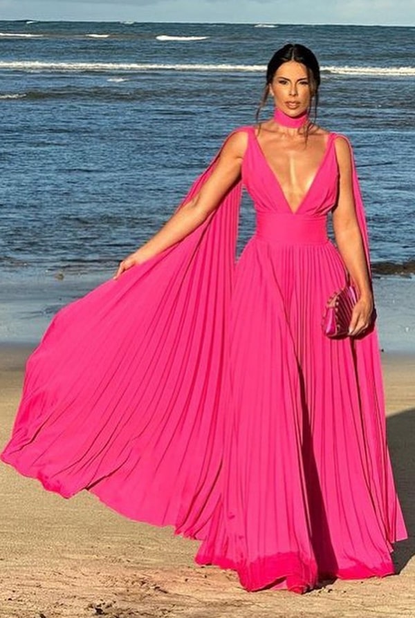 convidada de casamento na praia usando vestido rosa pink plissado com decote em v e manga capa