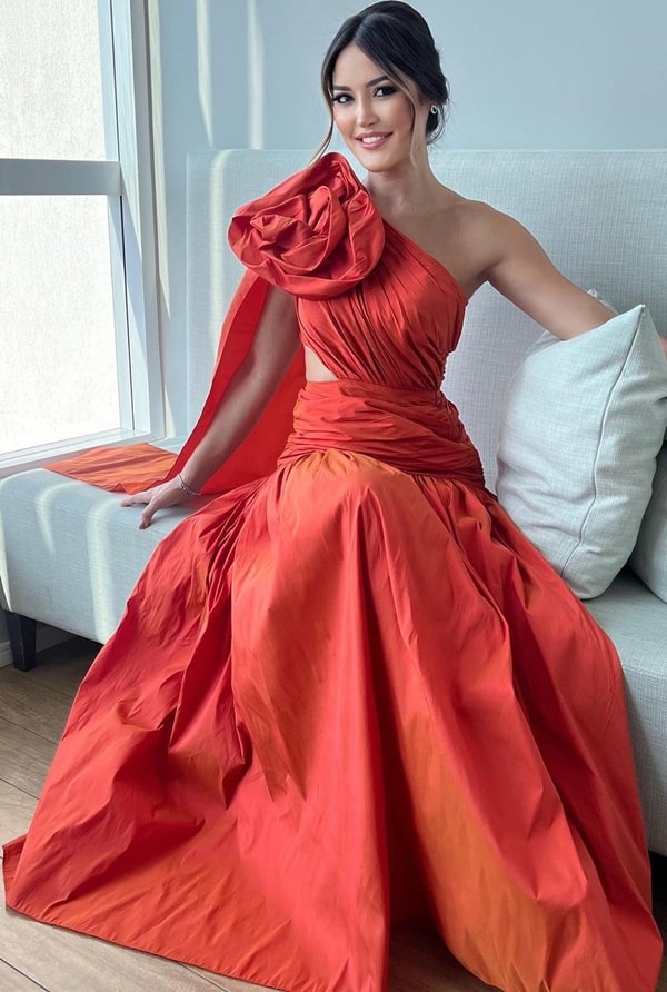 tendência da moda festa 2024: vestido de festa longo laranja com maxi rosa no ombro e drapeado na cintura