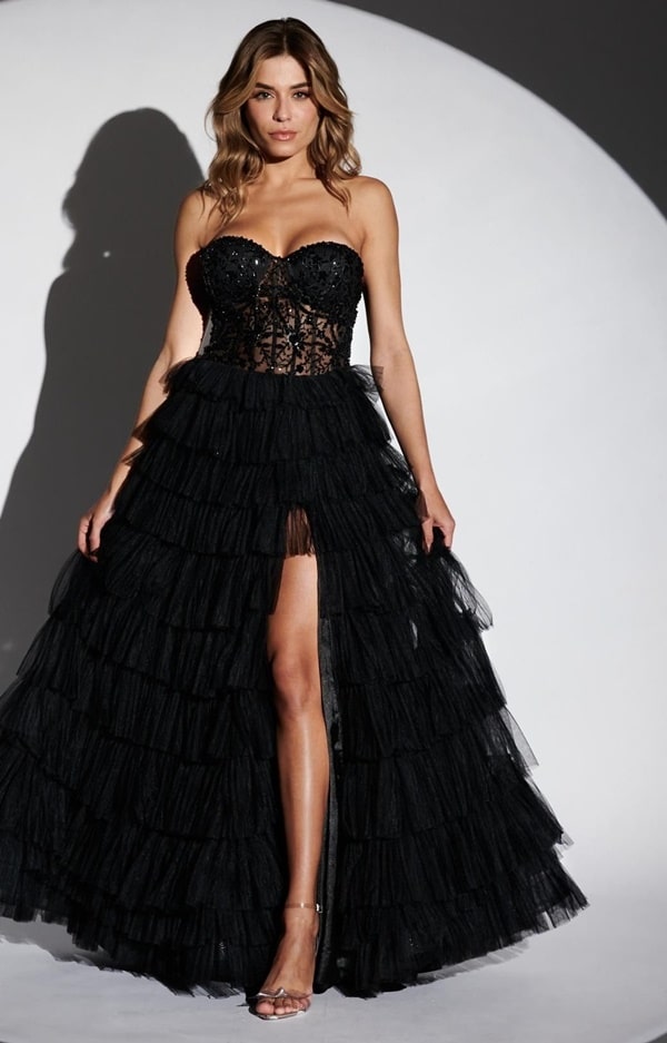vestido de festa longo preto com saia de tule em camadas e fenda frontal.  O vestido possui decote tomara que caia , corset bordado