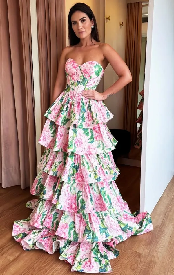vestido de festa longo com estampa floral rosa e verde. O vestido possui corselete com barbatanas, decote tomara que caia e saia em camadas