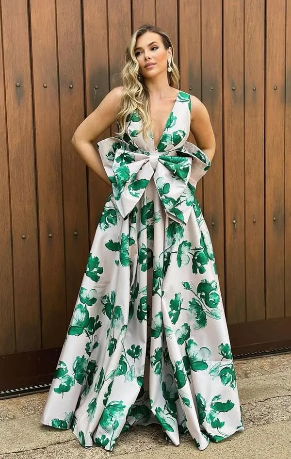 vestido de festa longo branco com estampa floral verde. O vestido possui maxi laço frontal