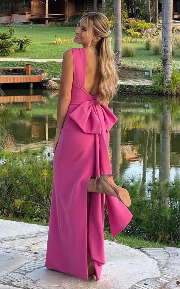 convidada de casamento ao ar livre durante o dia usando vestido de festa longo rosa justo com decote nas costas e laço