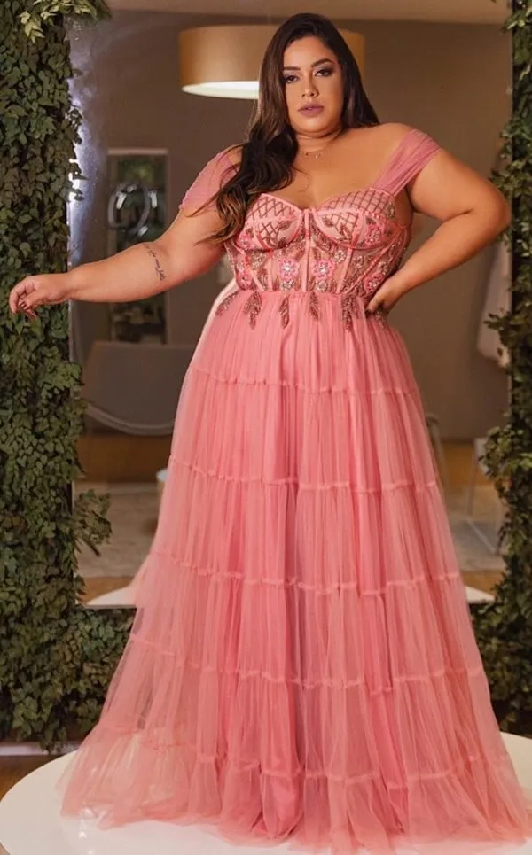 vestido de festa plus size de tule rose. O vestido possui saia fluida e corpete bordado com alças largas